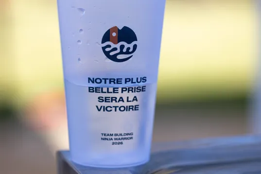 Un gobelet réutilisable « Notre plus belle prise sera la victoire » posé au soleil, pendant un team building