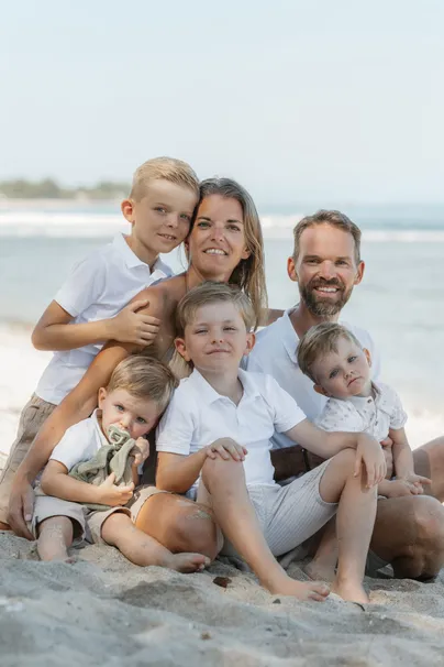 Une famille de six assise sur le sable, en tenues blanches