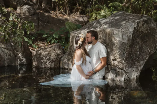 Un couple s’embrasse dans l’eau d’un bassin, la robe blanche flottant à la surface