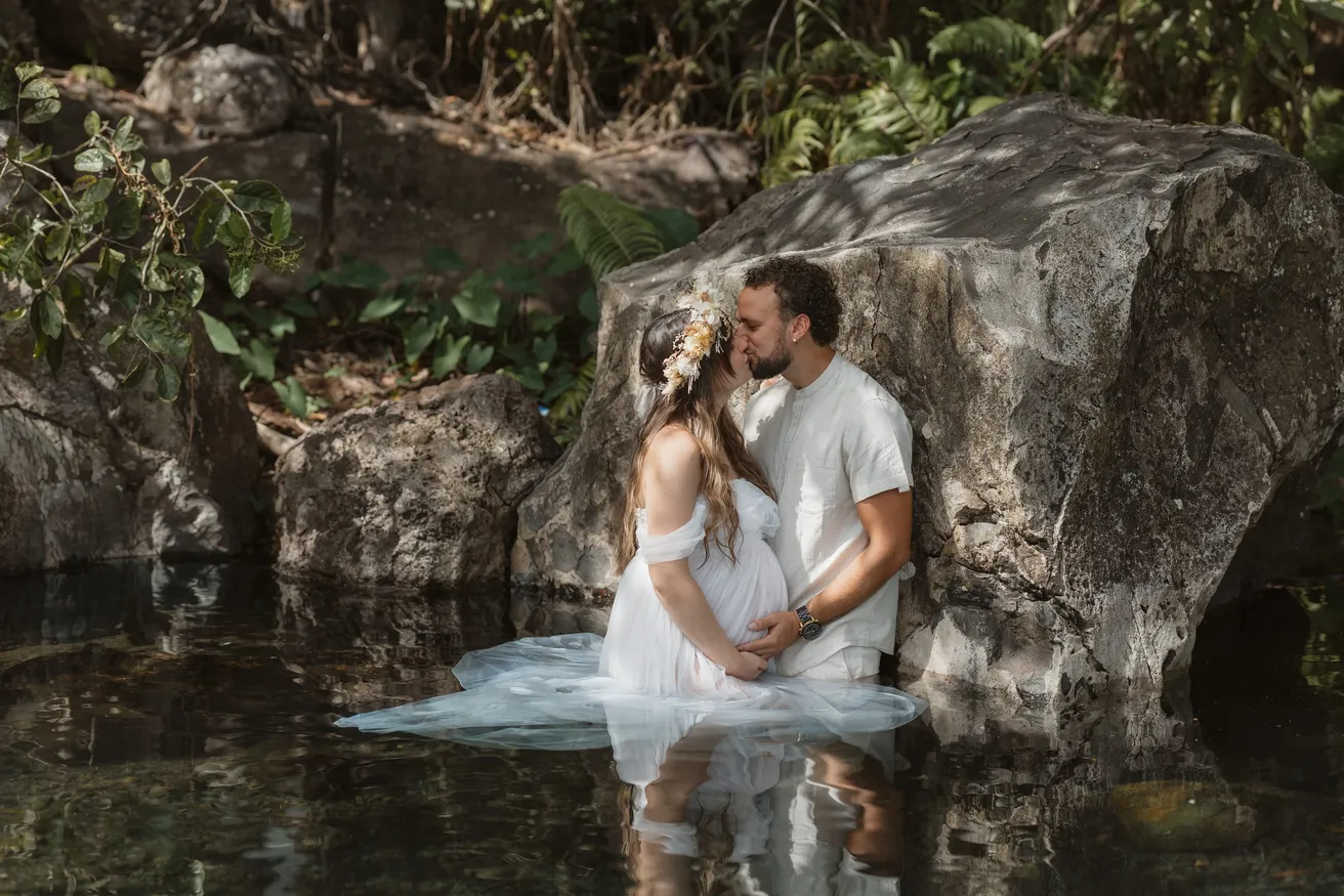 Un couple s’embrasse dans l’eau d’un bassin, la robe blanche flottant à la surface