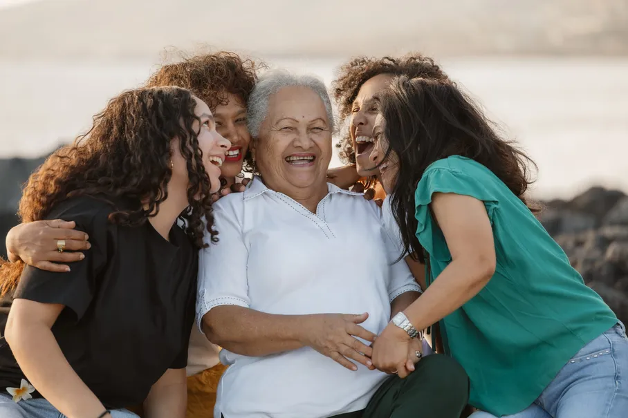 Trois générations enlacées autour de la grand-mère, en plein éclat de rire
