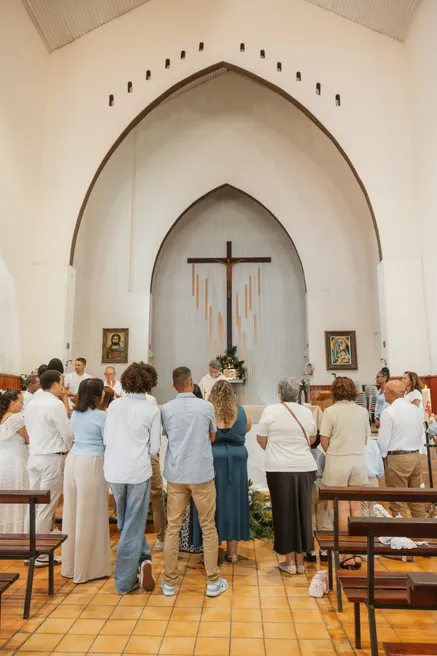 L’église vue du fond de la nef, les invités debout face à l’autel et à la croix