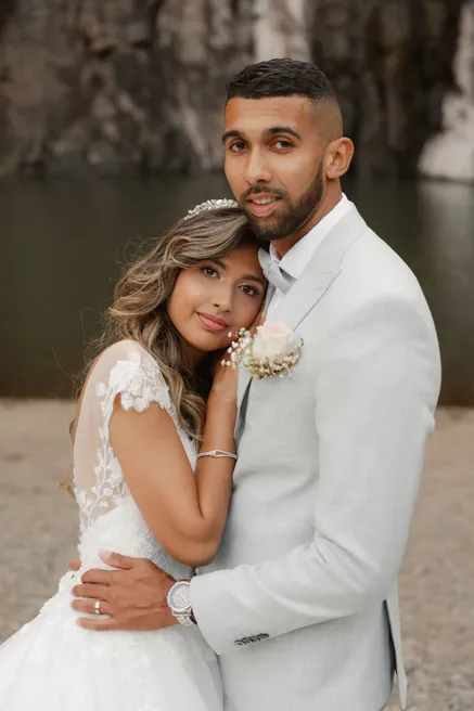 Les mariés enlacés, la mariée pose la tête contre le torse du marié en costume clair