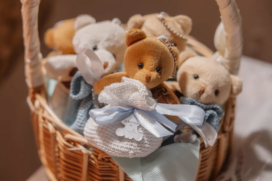 Des ours en peluche et des dragées en tulle bleu rangés dans un panier en osier