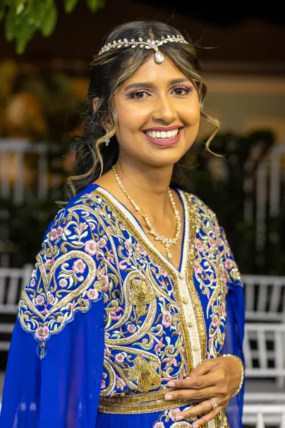 La mariée en tenue bleue brodée d’or, bijou frontal dans les cheveux, sourit face à l’objectif