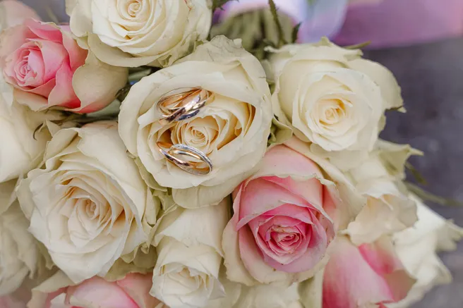 Les alliances posées sur un bouquet de roses blanches et roses