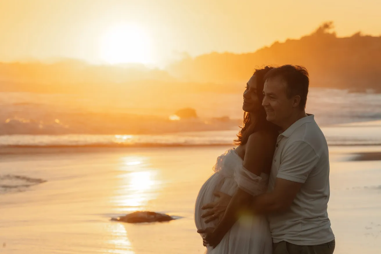 Un couple enlacé en silhouette face au soleil couchant sur la mer