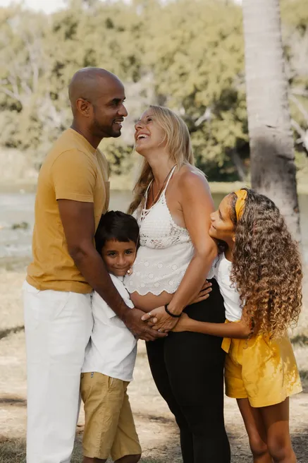 Une famille enlacée sous les arbres, les deux enfants serrés contre le ventre de la future maman
