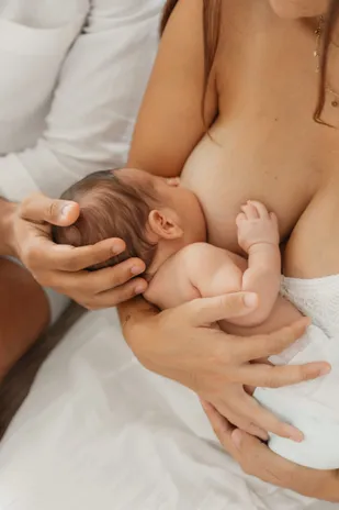 Une mère allaite son nouveau-né, qu’elle soutient d’une main sous la tête
