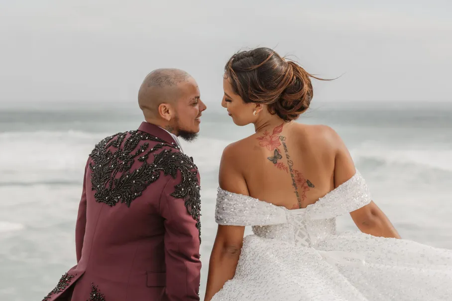 Les mariés se font face au bord de la mer, la mariée dos nu tatoué, le marié en veste brodée
