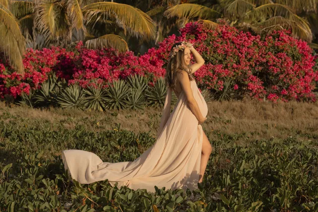 Longue robe beige et traîne déployée devant un massif de bougainvilliers roses