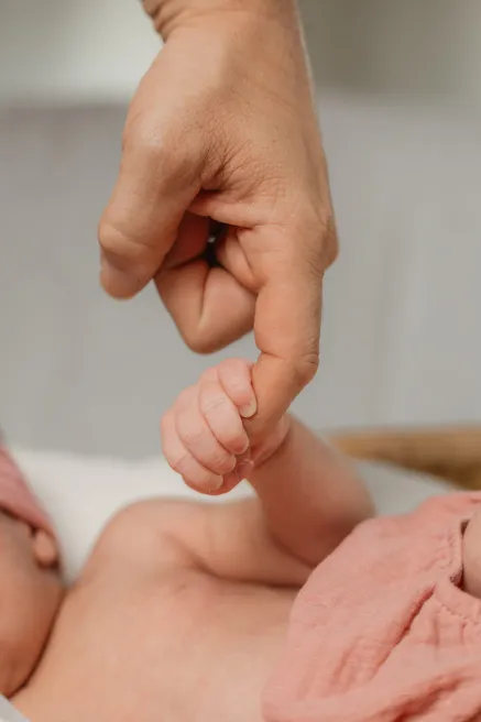 La main d’un nouveau-né serrée autour du doigt d’un adulte, en gros plan