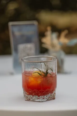 Cocktail orangé dans un verre ciselé, sur une table au décor bleu et fleurs séchées