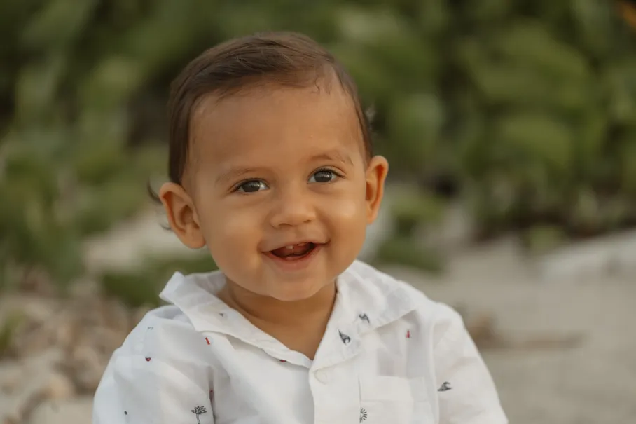 Portrait d’un petit garçon qui sourit, la végétation derrière lui