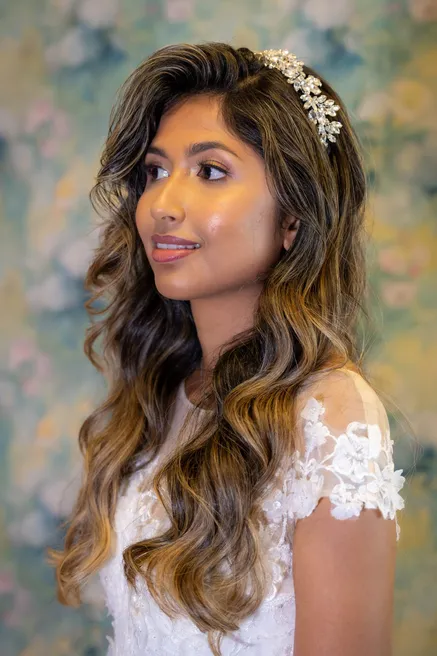 La mariée de profil, longs cheveux ondulés et diadème, devant un décor peint fleuri