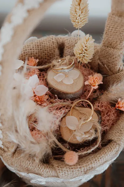 Porte-alliances en rondelles de bois dans une coupe de jute ornée de fleurs séchées