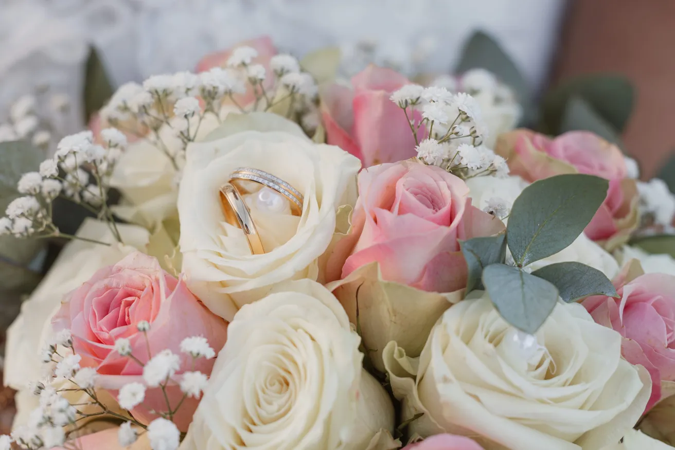 Les alliances posées au creux d’un bouquet de roses blanches et roses et de gypsophile