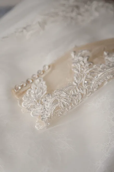 Détail de la ceinture brodée de perles et de dentelle d’une robe de mariée ivoire
