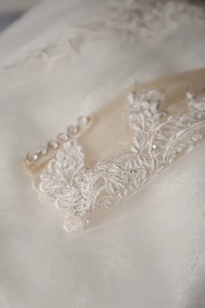 Détail de la ceinture brodée de perles et de dentelle d’une robe de mariée ivoire