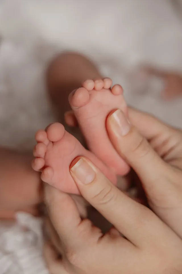 Les petits pieds d’un nouveau-né tenus dans les mains de sa maman