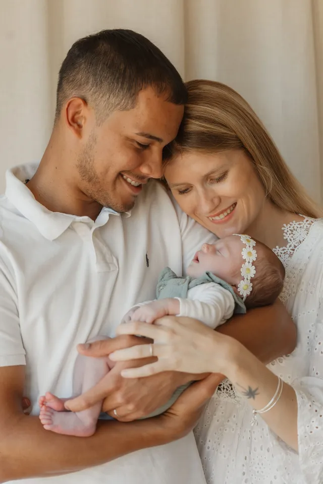 Les parents penchés sur leur bébé endormi, qu’ils tiennent ensemble dans leurs bras