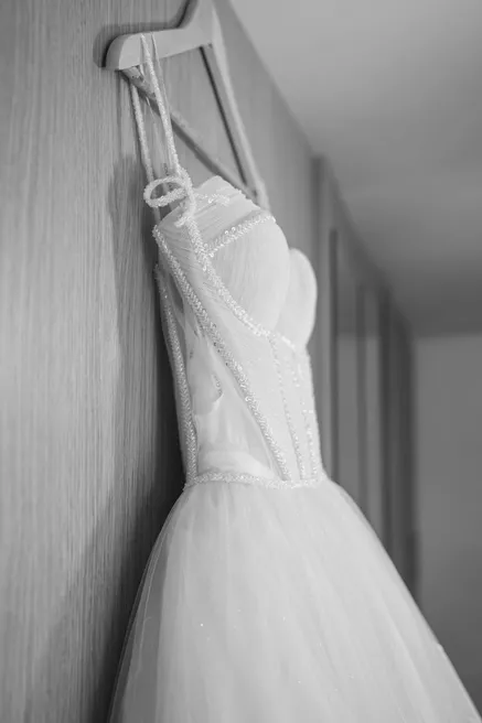 En noir et blanc, la robe de mariée bustier suspendue à un crochet contre un mur