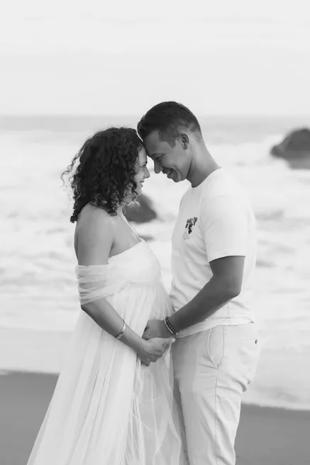 En noir et blanc, un couple front contre front, mains réunies sur le ventre