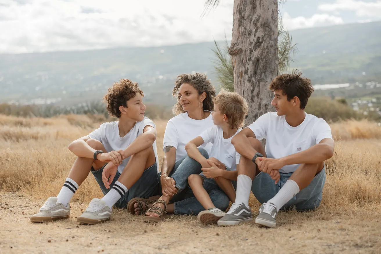 Une mère et ses trois fils assis dans les herbes sèches, la montagne en arrière-plan