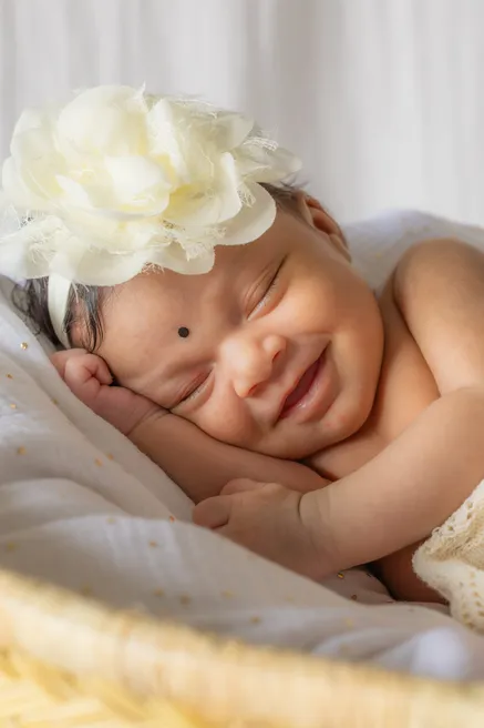 Le nouveau-né sourit en dormant, une grande fleur ivoire dans les cheveux