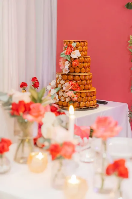 Pièce montée de choux ornée de fleurs rouges, sur une table de bougies et d’anémones