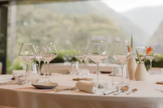 Table dressée de verres à pied et d’une fleur d’oiseau de paradis, face aux montagnes