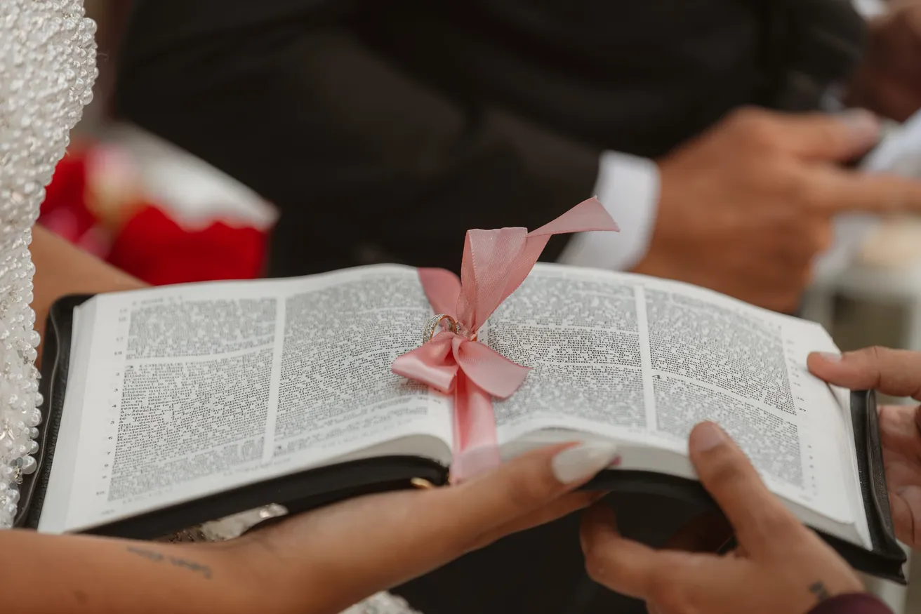 Mains tenant une bible ouverte, fermée d’un ruban rose, pendant la cérémonie