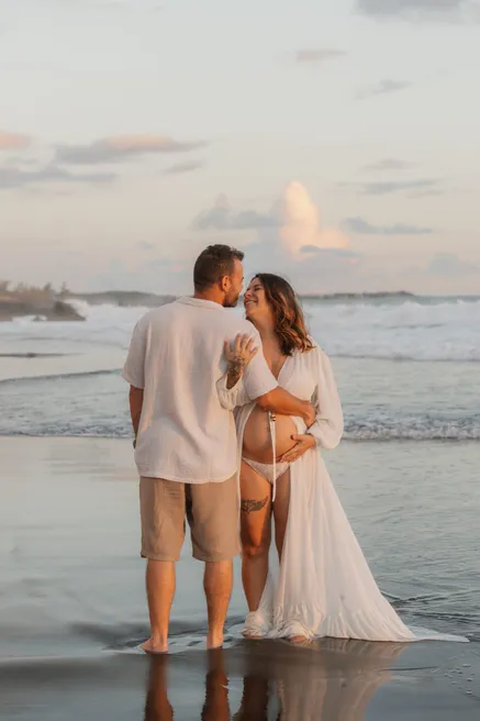 Un couple de dos, pieds dans l’eau, au coucher du soleil