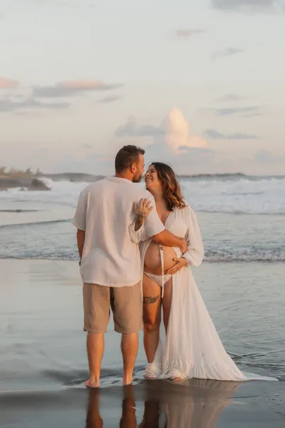 Un couple de dos, pieds dans l’eau, au coucher du soleil