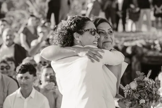 En noir et blanc, la mariée serre une invitée dans ses bras au milieu de la foule