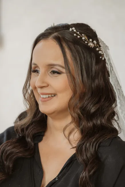 La mariée sourit pendant les préparatifs, voile et bijou de cheveux, en chemise noire