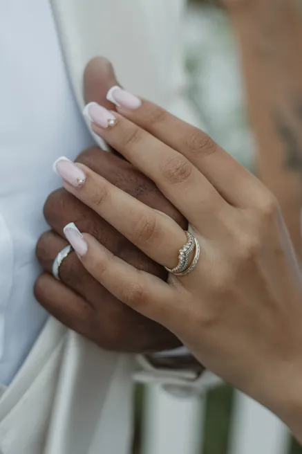 Mains enlacées des mariés, bague et alliance à l’annulaire de la mariée
