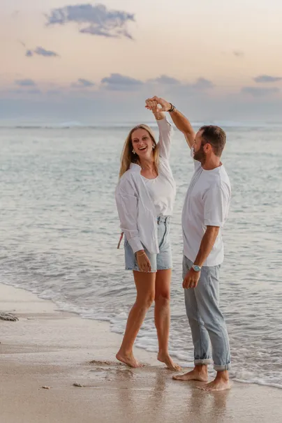 Un couple danse au bord de l’eau, il fait tourner sa compagne sous son bras levé