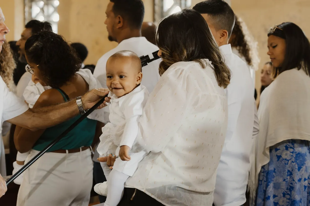 Pendant la cérémonie, un bébé en blanc porté au milieu des invités en tenue claire