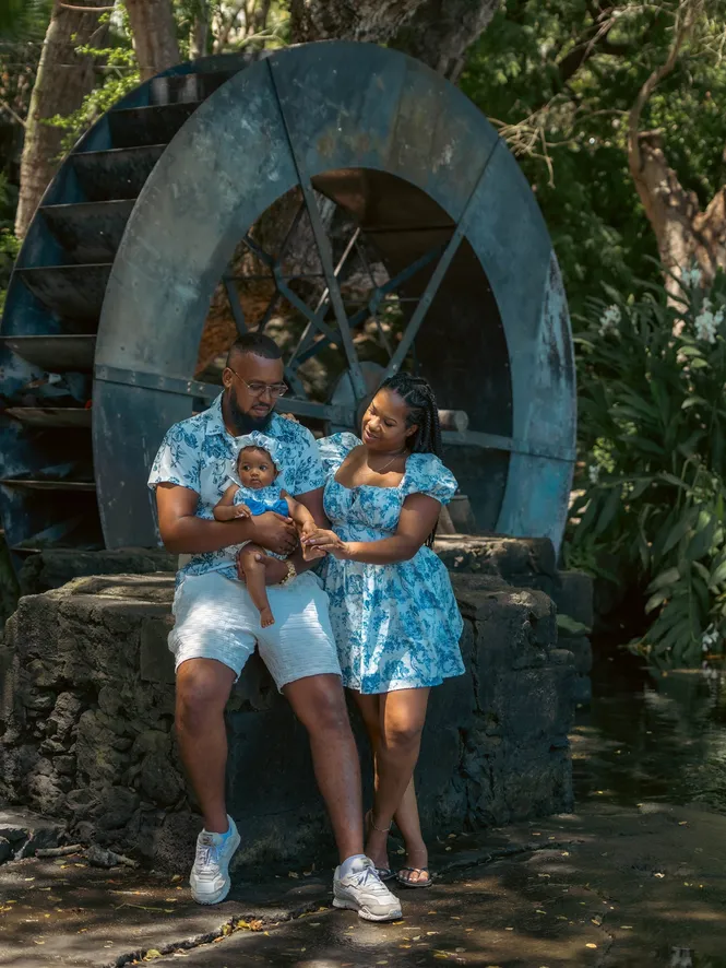 La famille en tenues assorties bleues pose devant une vieille roue à eau