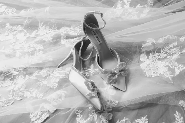 En noir et blanc, les escarpins de la mariée posés sur son voile de dentelle