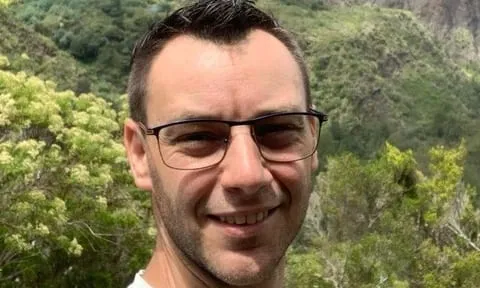 Adrien, vidéaste et fondateur d’AGV Production, sourire et lunettes, devant les hauts de l’île